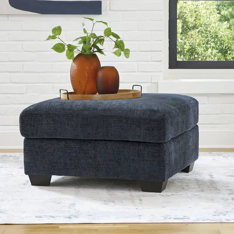 Pouf poggiapiedi di grandi dimensioni rivestito con piedini a vista in simil-legno